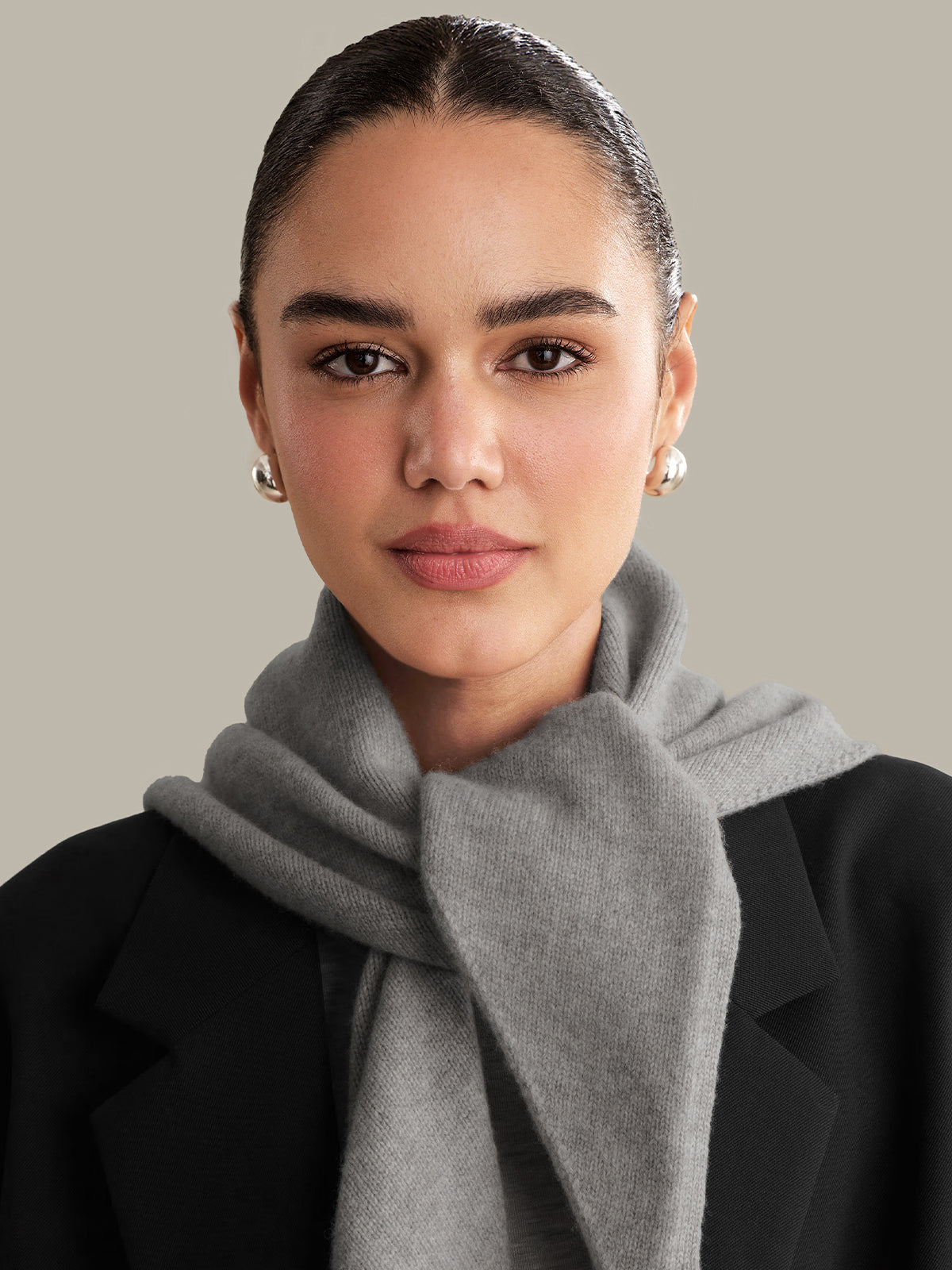 Woman wearing a gray scarf with a neutral background
