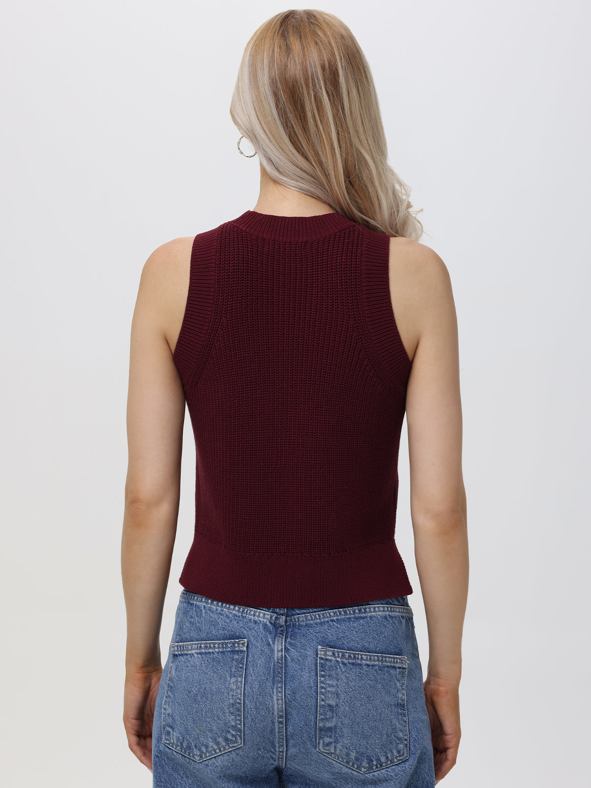 A person with long blonde hair is seen from the back, wearing a 525 America sleeveless crew neck ribbed burgundy top and blue denim jeans, creating a casual look against a plain light background.
