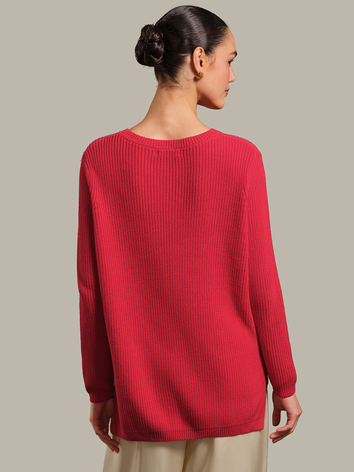Woman wearing a red sweater against a beige background