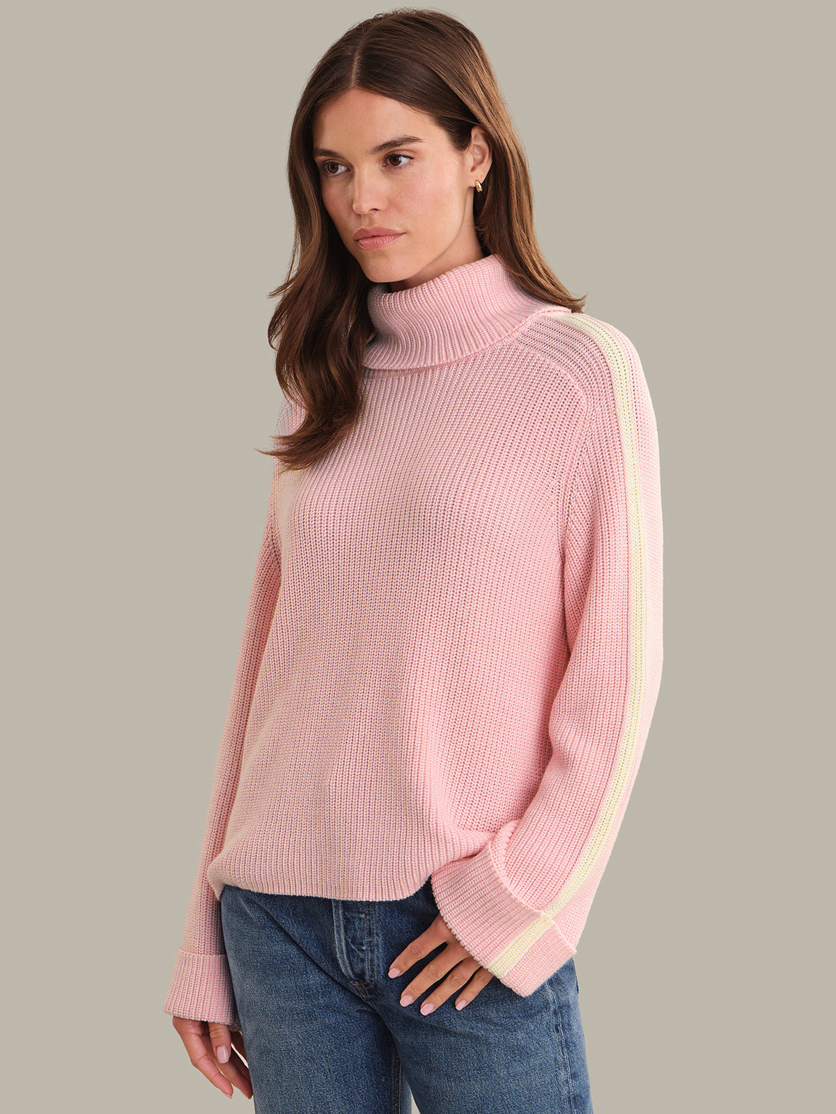 Woman wearing a pink sweater with a white stripe on a gray background