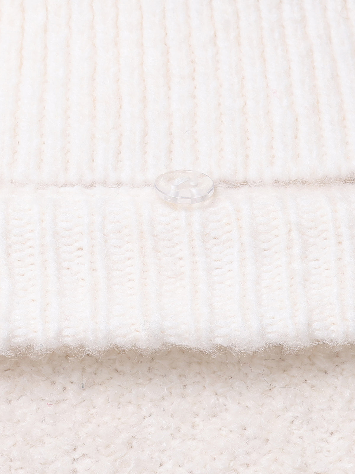 Close-up of a cream-colored woolen sweater from 525 America, featuring a clear plastic button and ribbed texture on the upper part with a soft, fuzzy texture below. Raglan sleeves enhance its charm, and the button is centrally located on the ribbed section for a classic look.