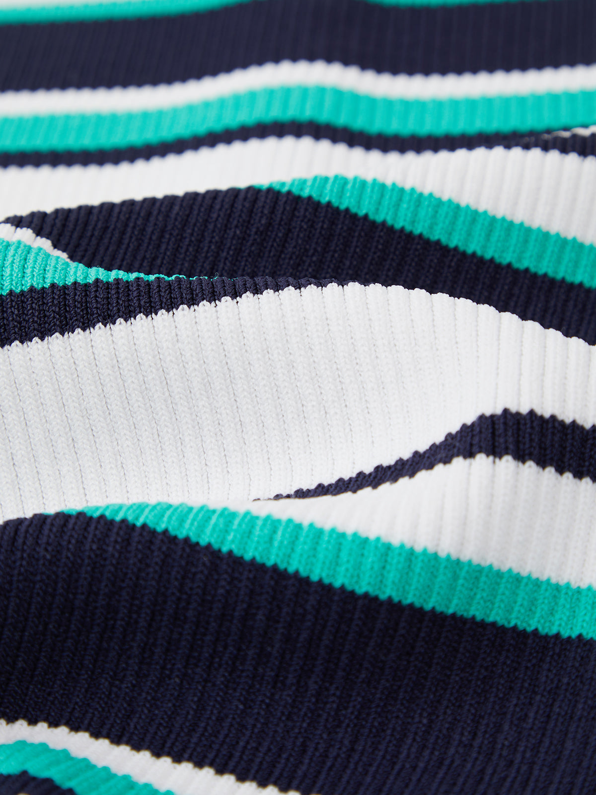 Close-up of ribbed fabric from 525 America with navy blue, white, and teal horizontal stripes. The stretchy sweater-tank material has a wavy texture, adding shadows and detail to the cropped fit.