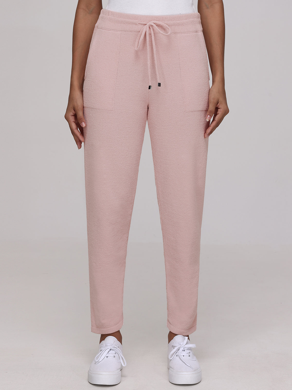 A person in 525 Americas light pink jogger pants made from plush fabric, featuring a drawstring waist and pockets, paired with white sneakers against a plain light background.