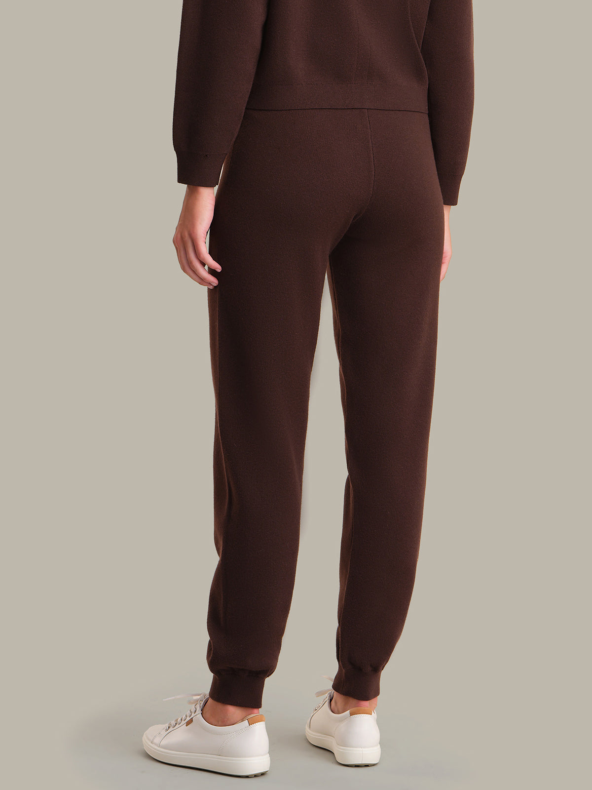 Brown sweatpants worn by a person on a gray background
