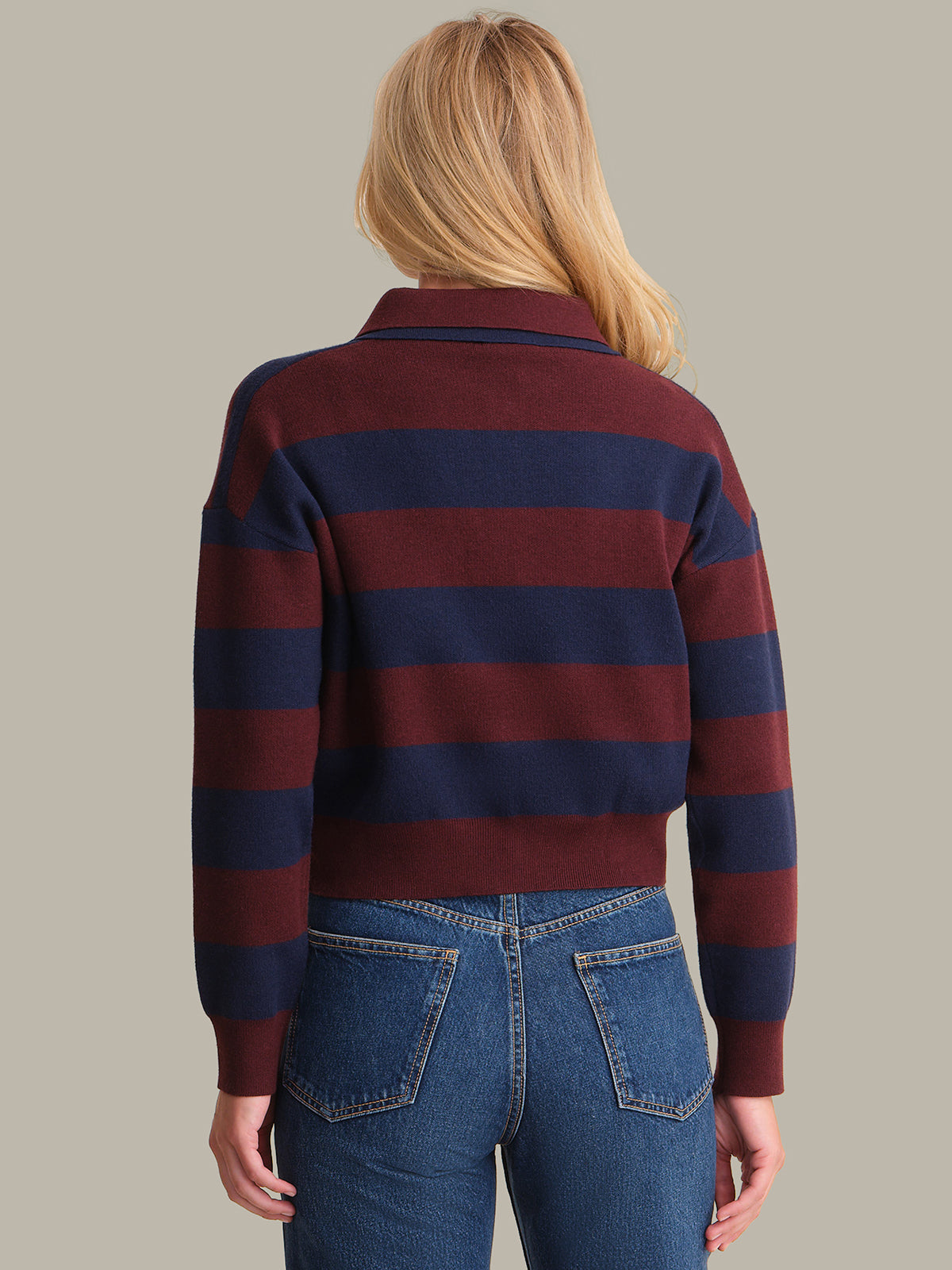 Person wearing a striped sweater and jeans on a plain background