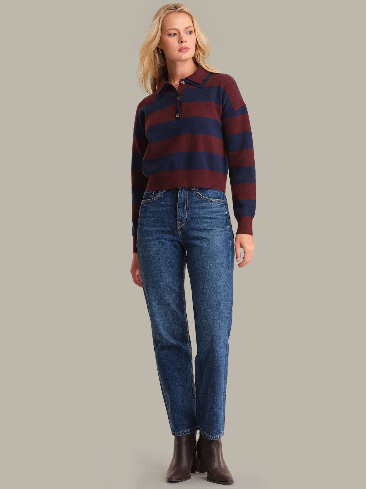 Woman wearing a striped shirt and jeans on a plain background
