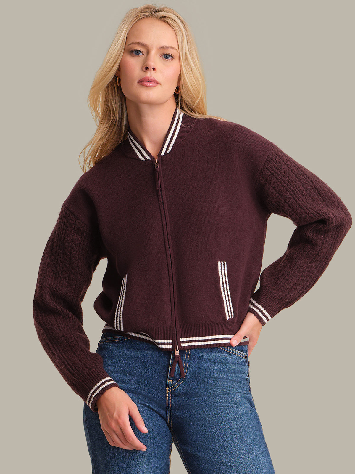 Woman wearing a maroon sweater with white trim on a neutral background