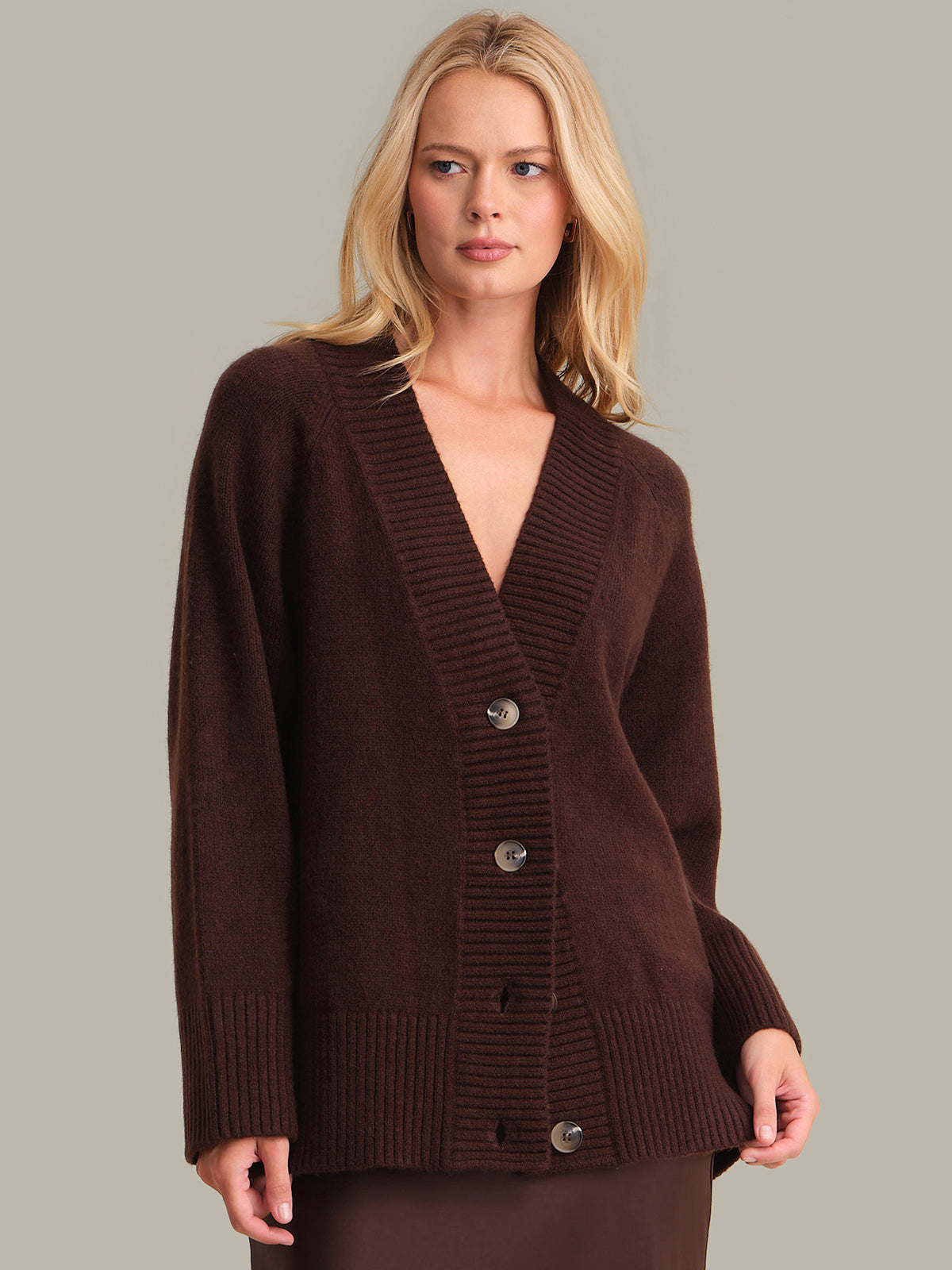 Woman wearing a brown cardigan against a neutral background