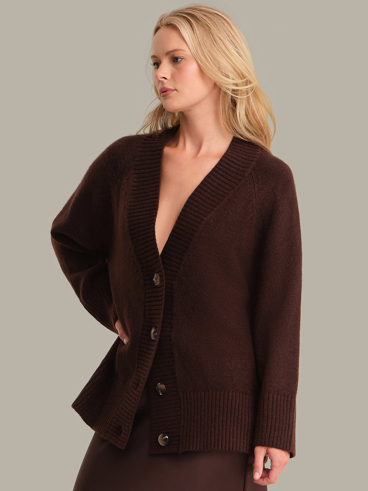 Woman wearing a brown cardigan against a plain background