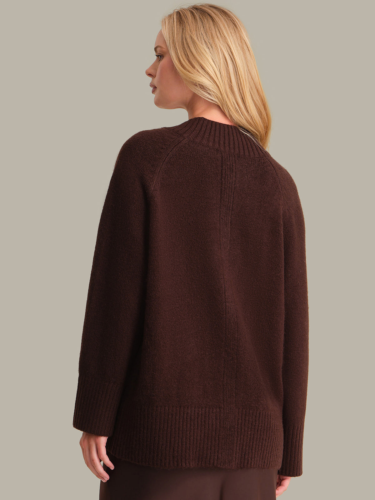 Woman wearing a brown sweater against a plain background
