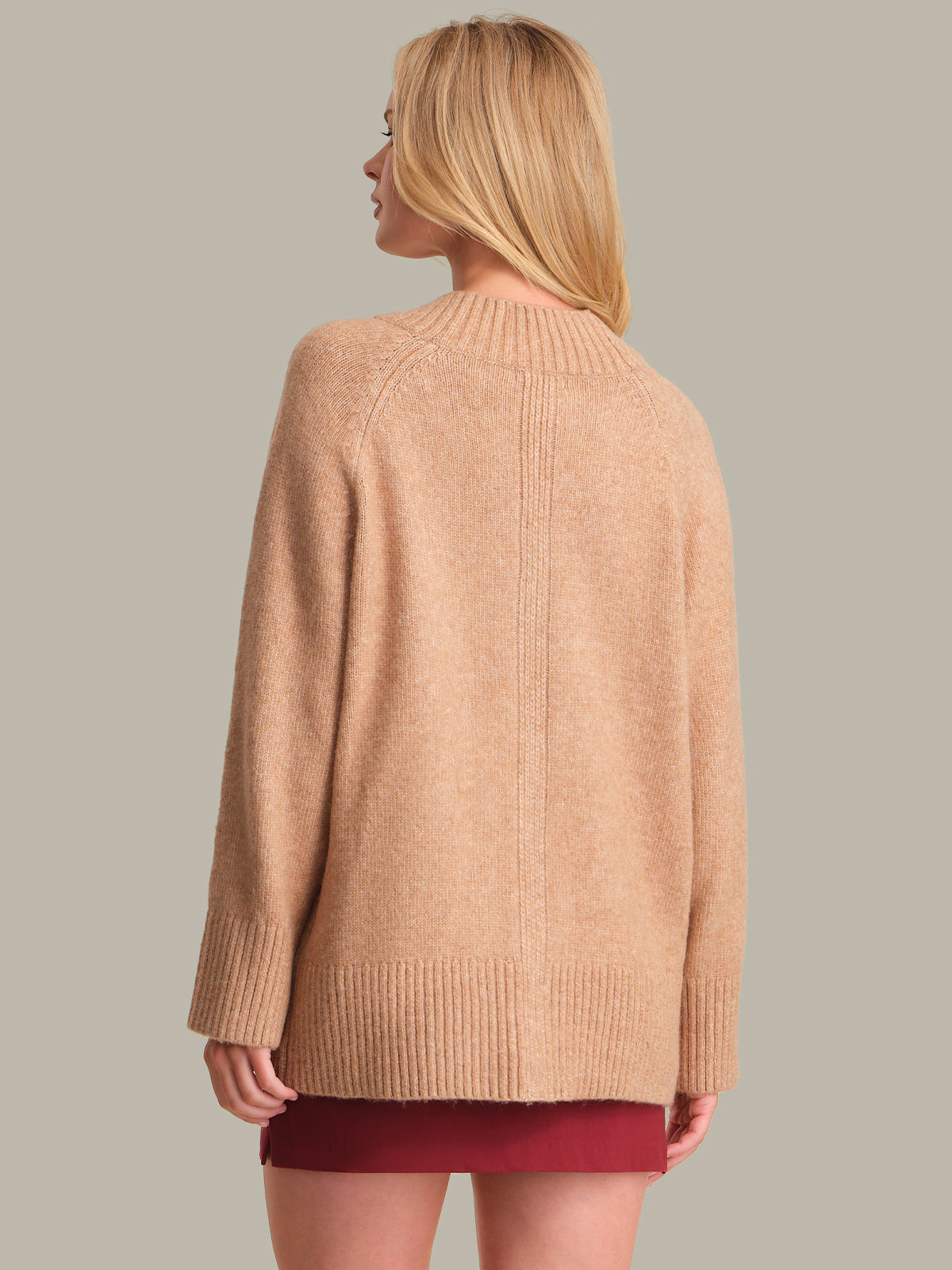 Woman wearing a beige sweater against a plain background
