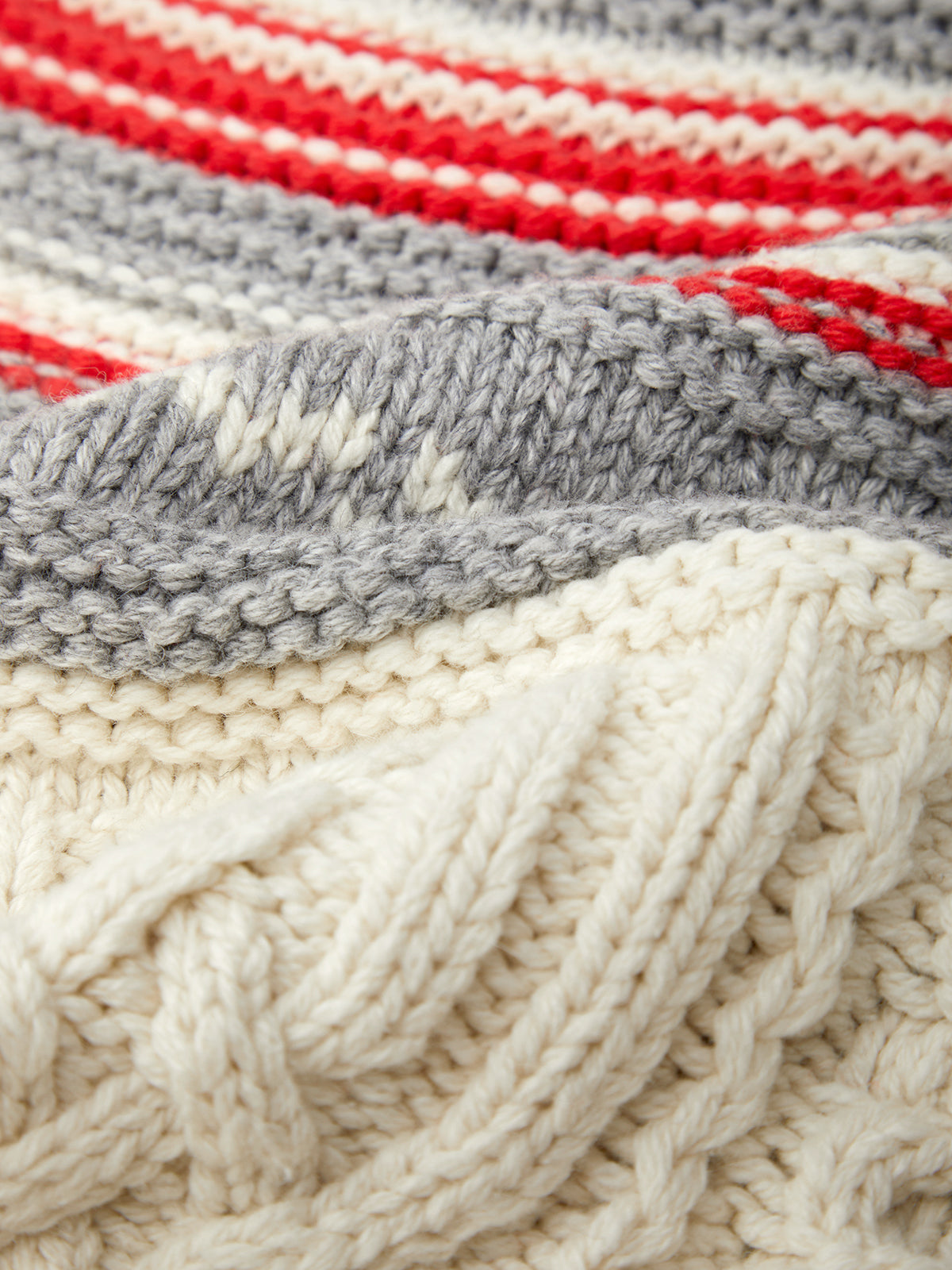 Close-up of a knitted fabric with red, gray, and white stripes.
