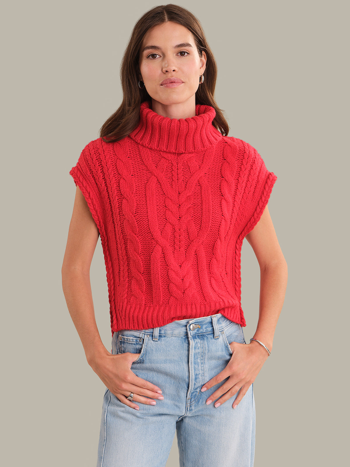 Woman wearing a red knitted sleeveless sweater against a neutral background