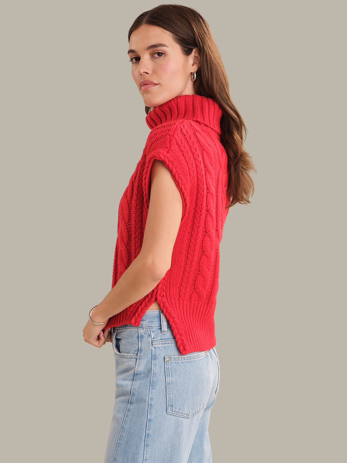 Woman wearing a red knitted vest against a gray background