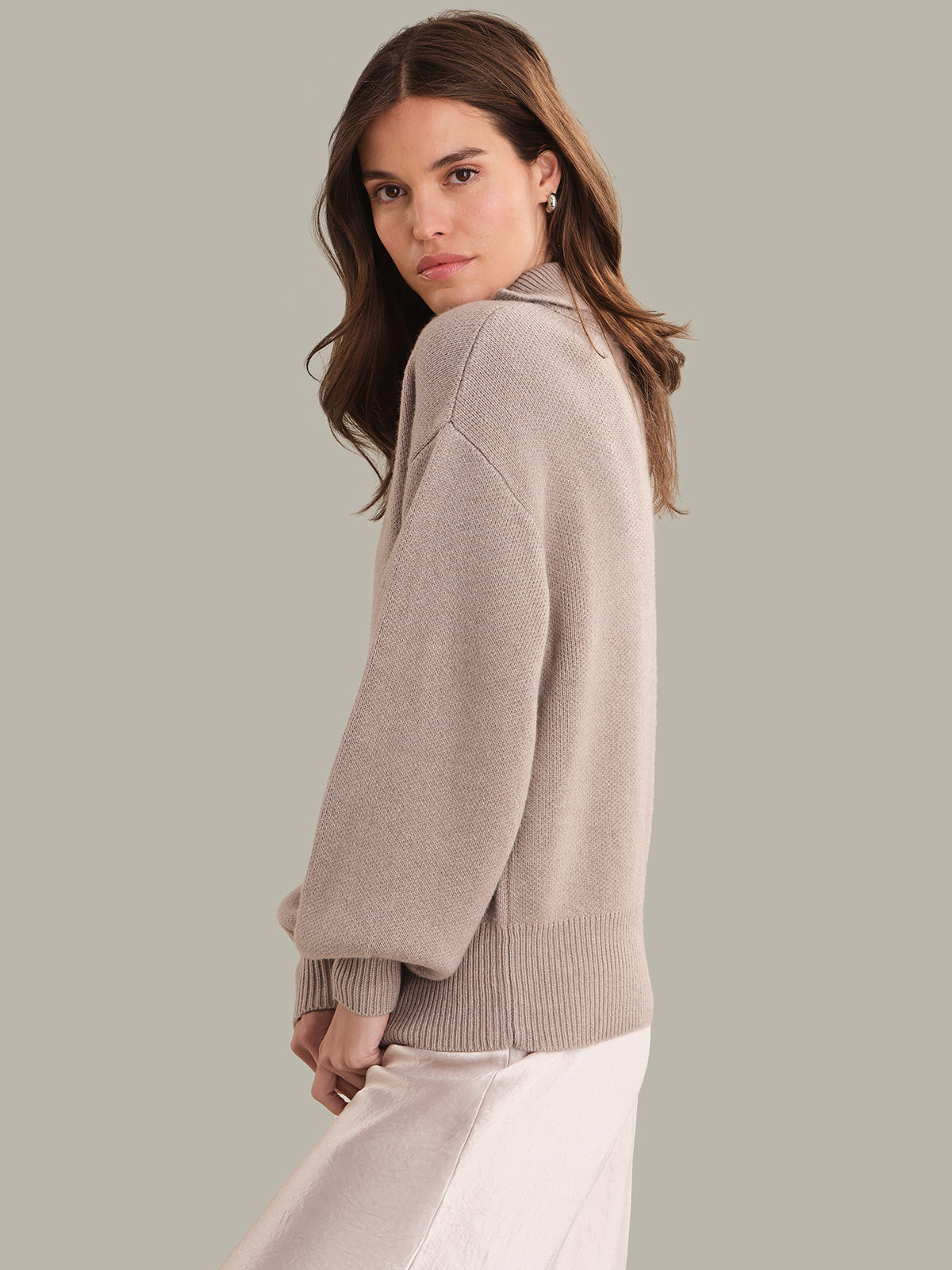 Woman wearing a beige sweater against a plain background