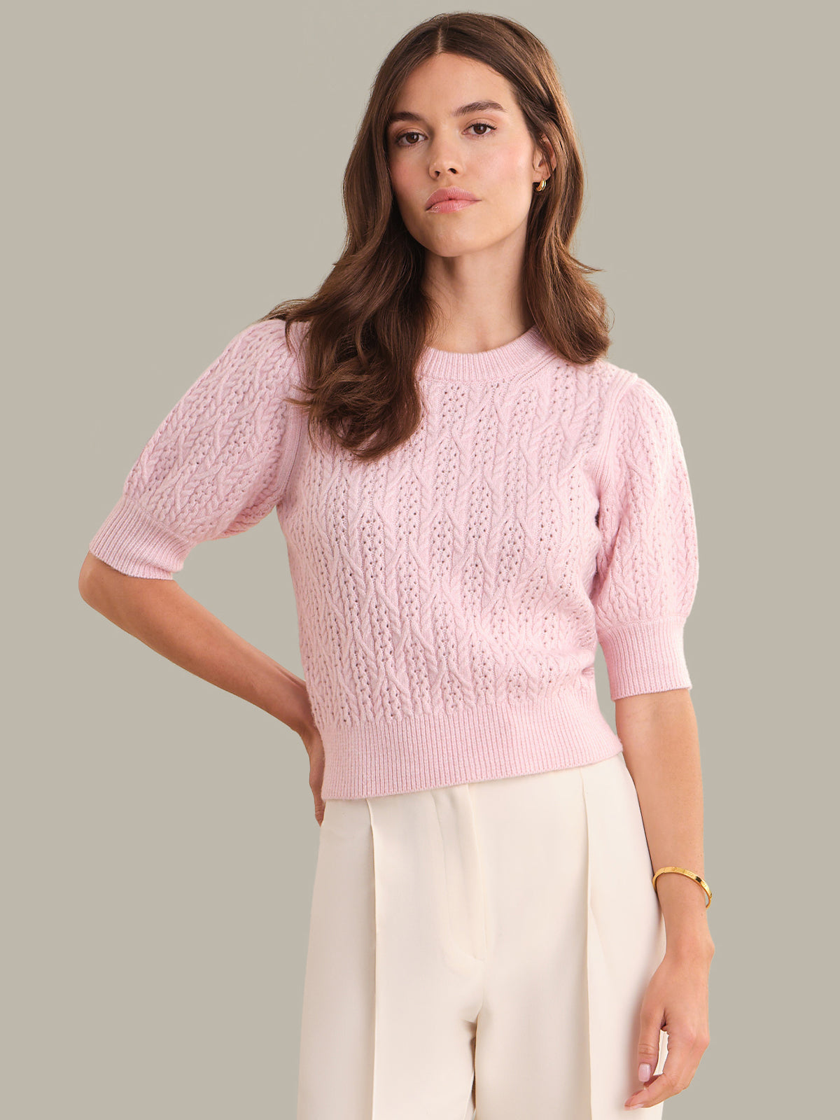 Woman wearing a pink knitted sweater against a neutral background