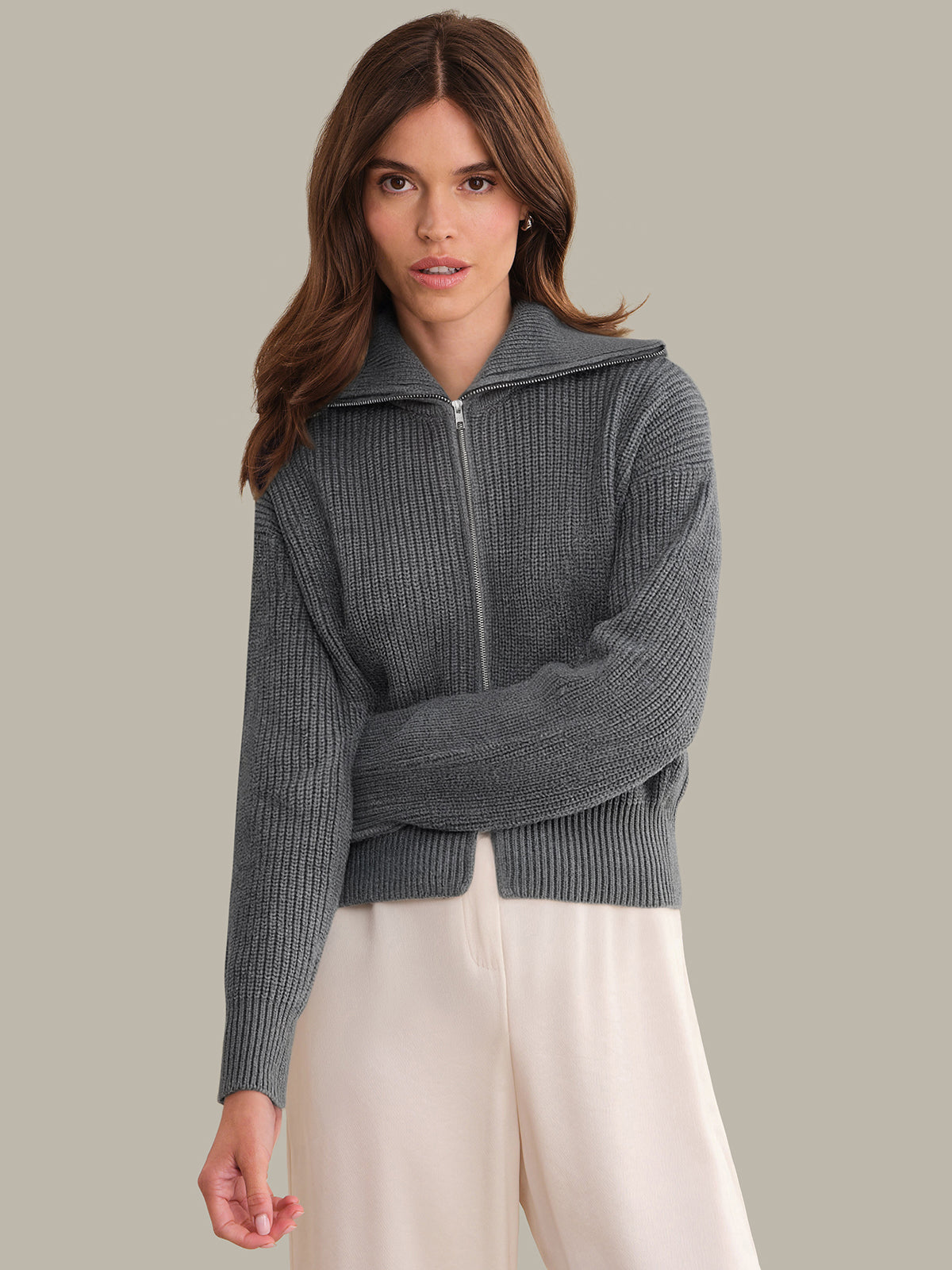 Woman wearing a gray zip-up sweater with a neutral background