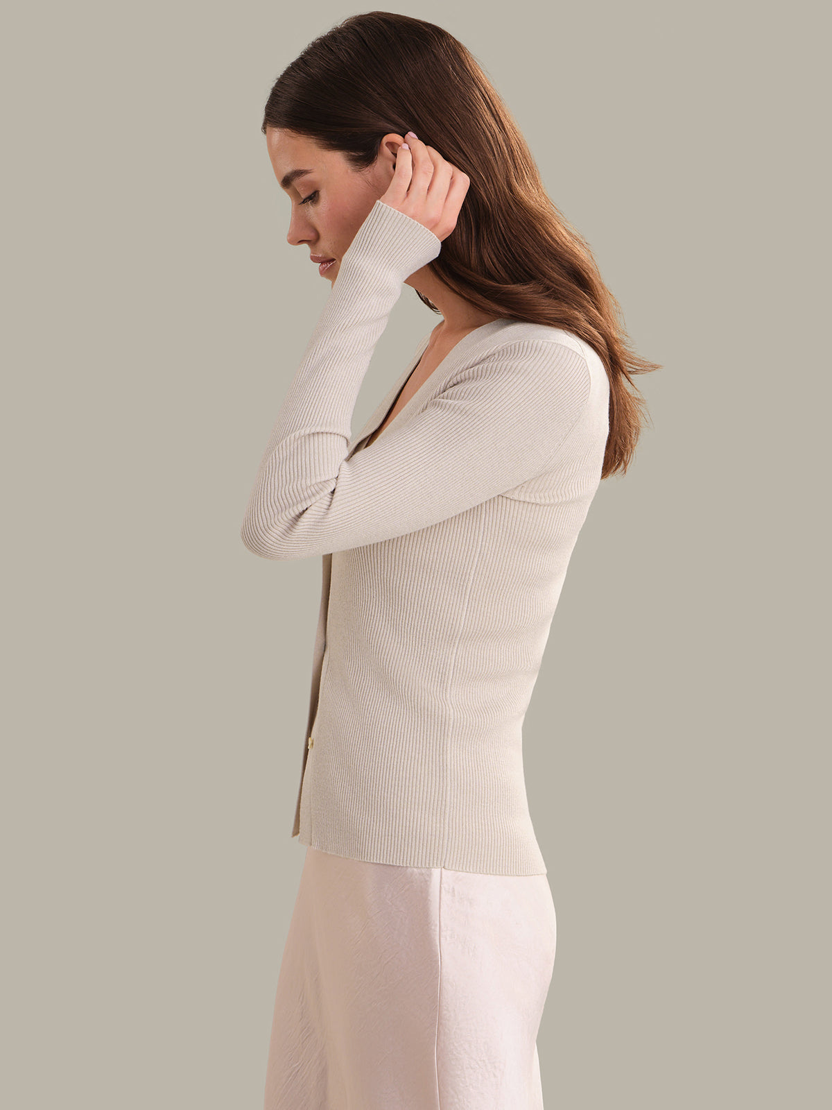 Woman wearing a light beige cardigan against a plain background