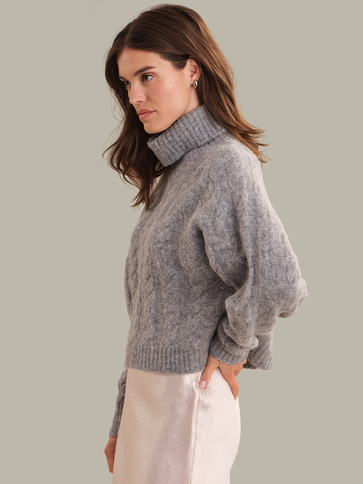 Woman wearing a gray sweater against a plain background
