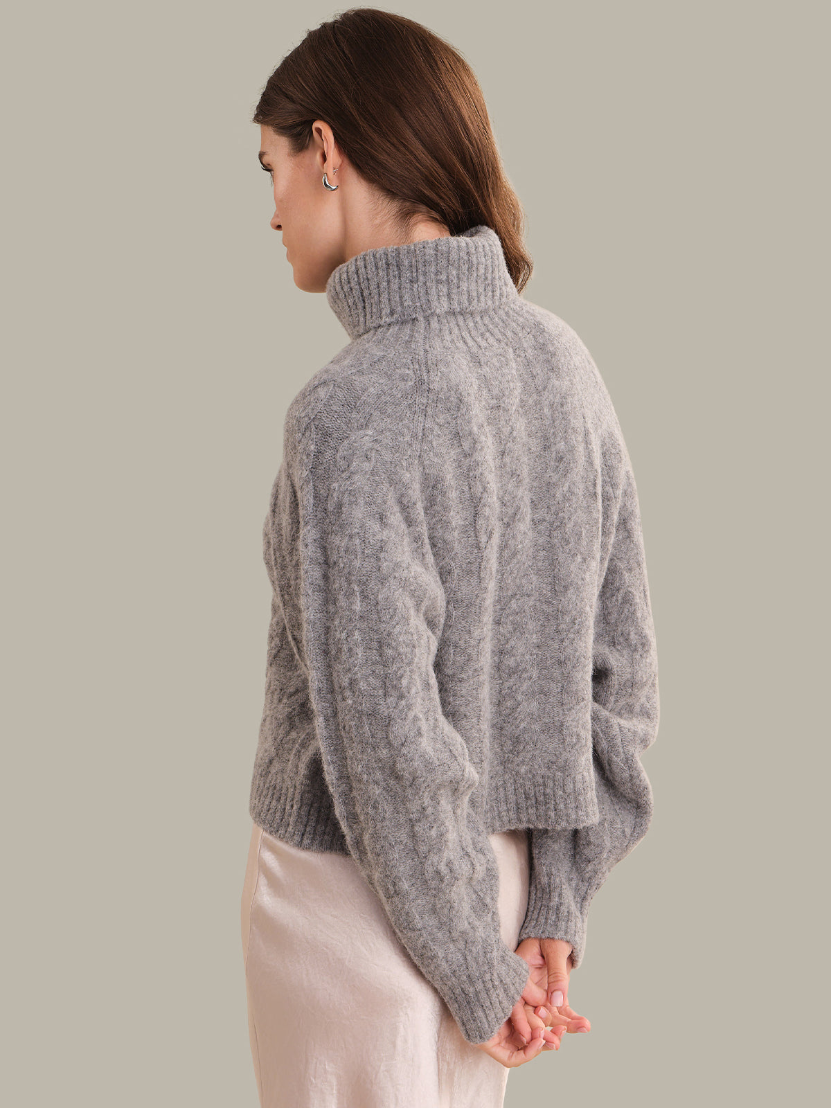 Person wearing a gray sweater against a plain background