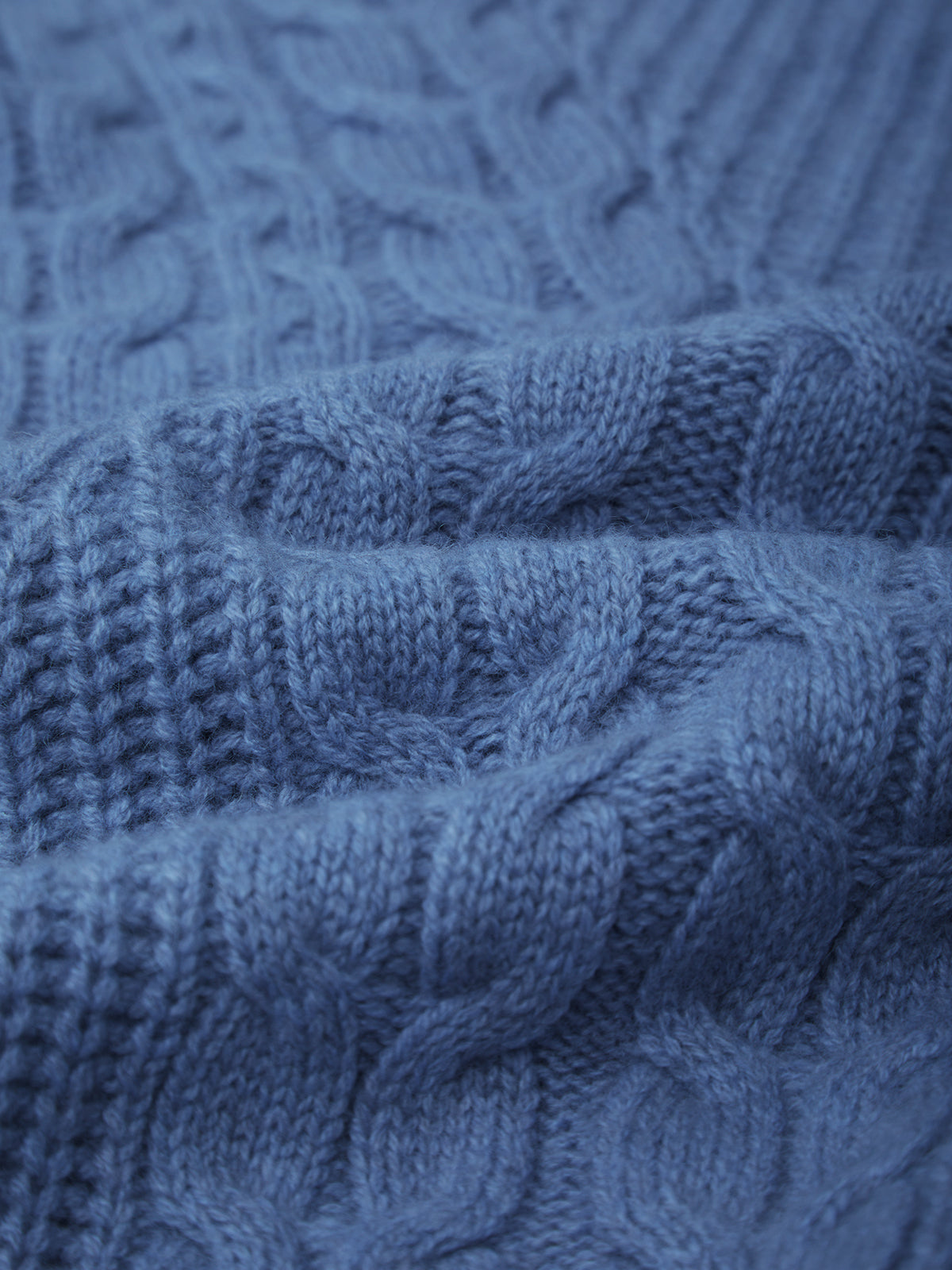 Close-up of a blue knitted fabric with cable pattern