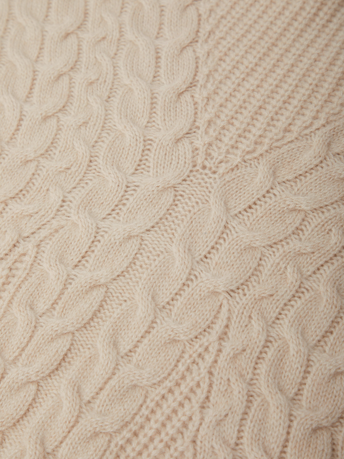 Close-up of beige knitted fabric with cable pattern