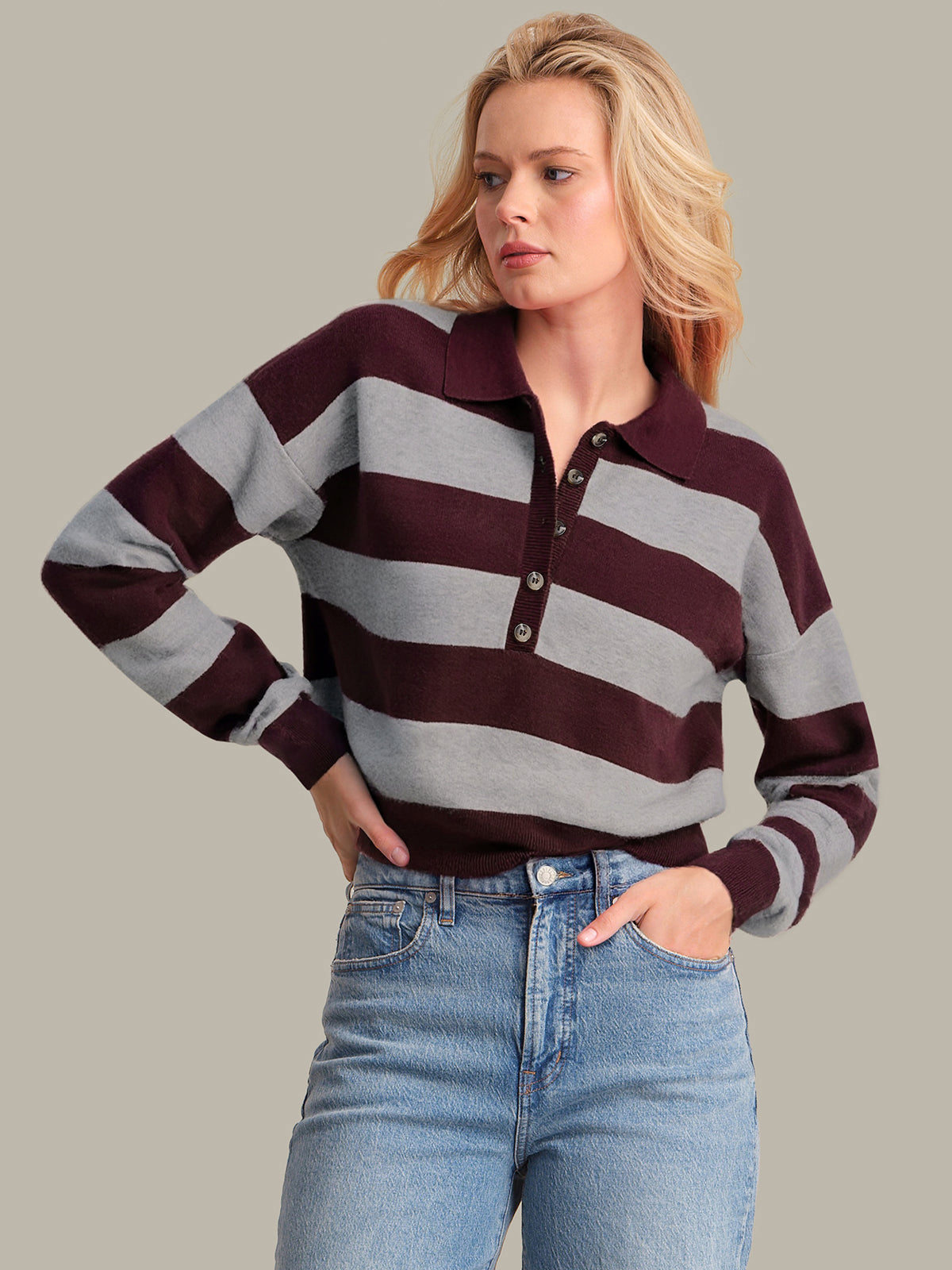 Woman wearing a striped sweater and jeans against a neutral background