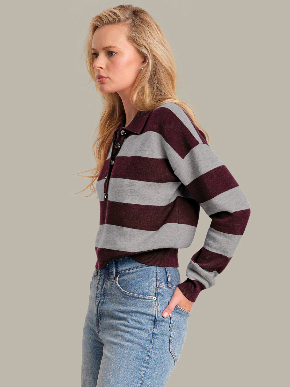 Woman wearing a striped sweater and jeans against a plain background