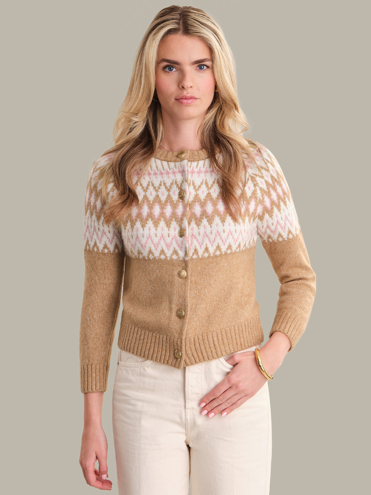 Woman wearing a beige and white patterned sweater against a plain background