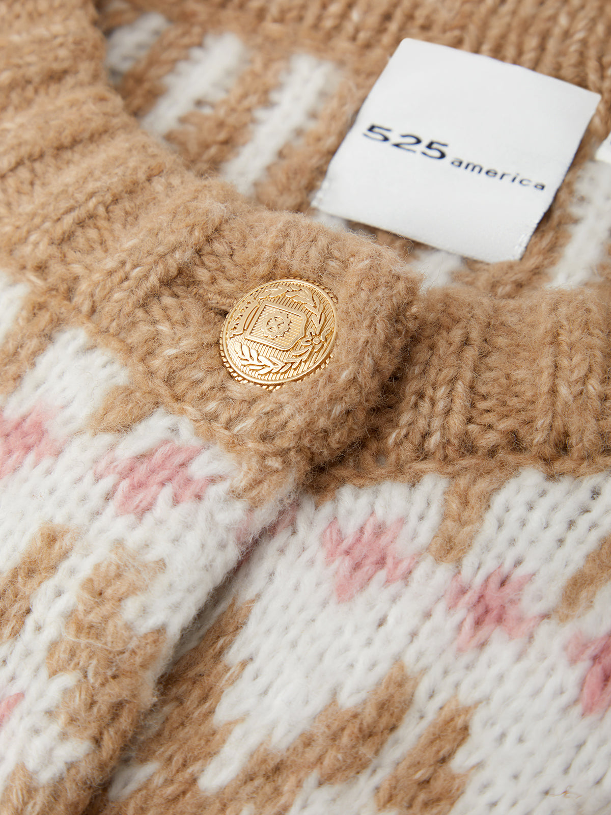 Close-up of a textured fabric with a gold button and a white tag displaying '525 america'.
