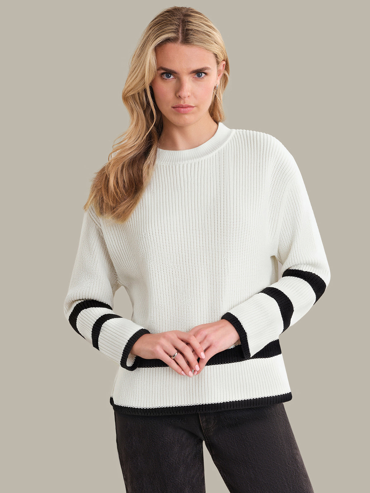 Woman wearing a white sweater with black stripes on a plain background