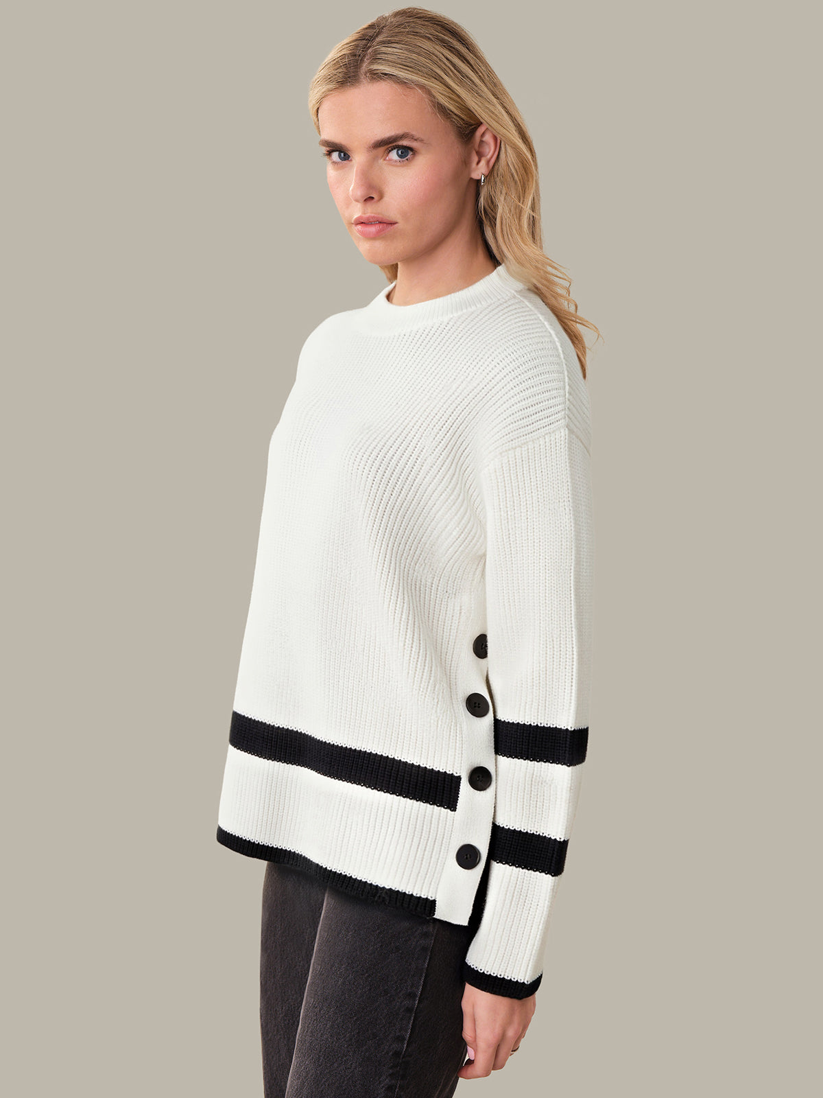 Woman wearing a white sweater with black accents on a beige background