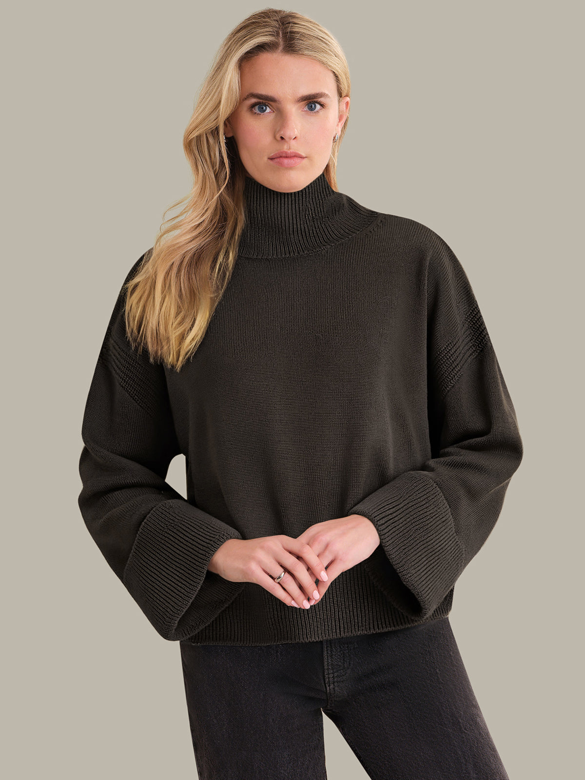 Woman wearing a brown turtleneck sweater against a plain background