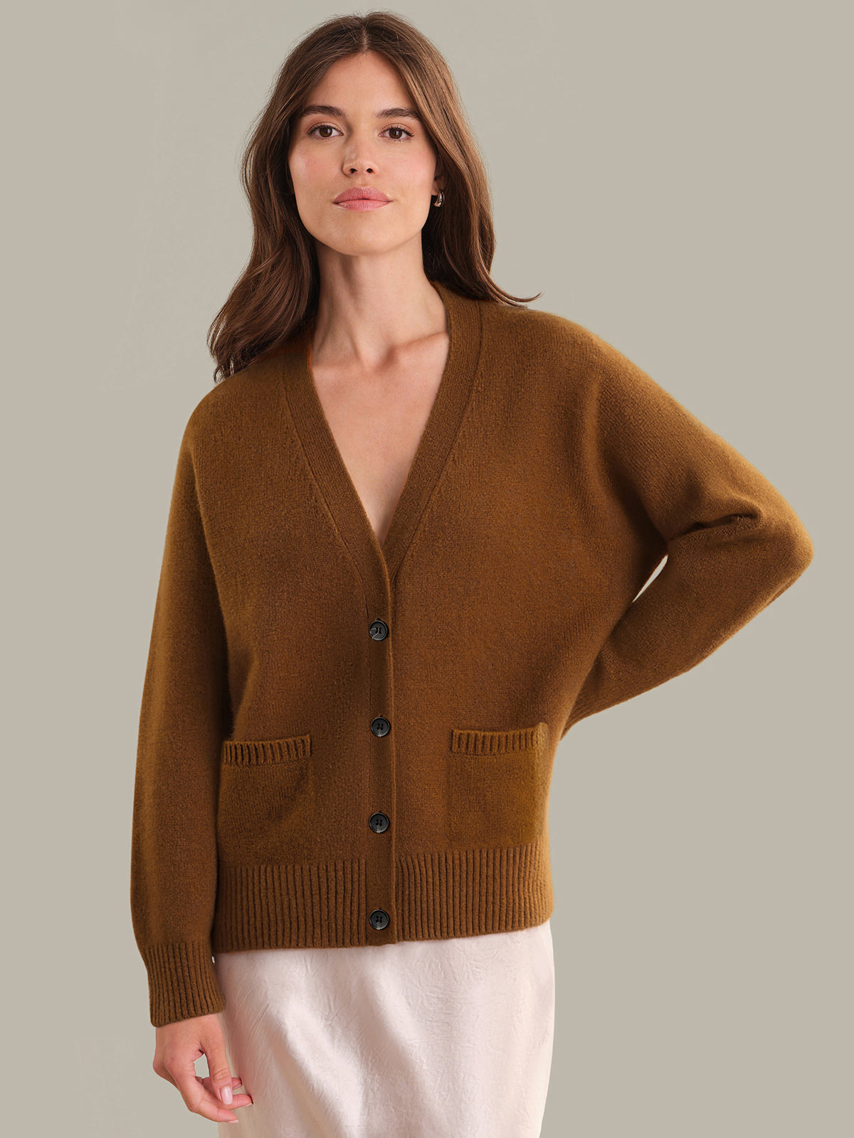 Woman wearing a brown cardigan against a neutral background