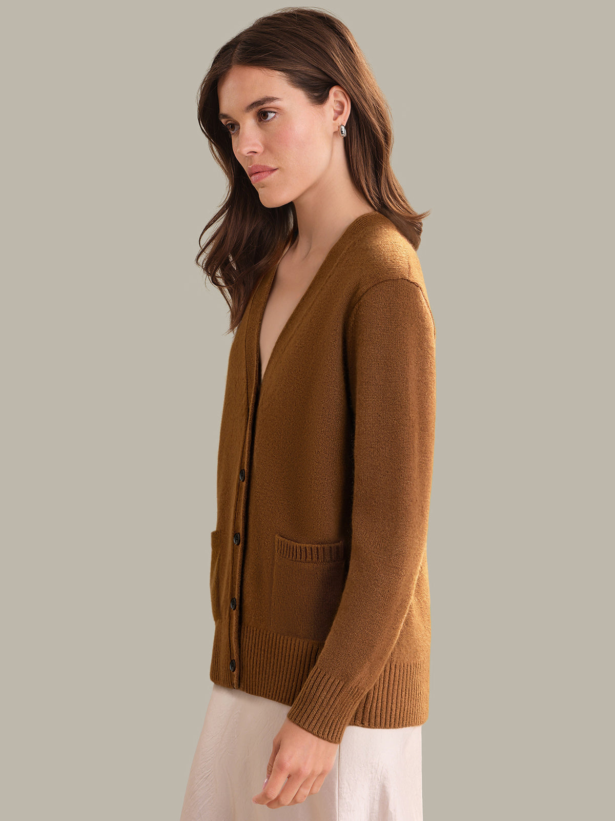 Woman wearing a brown cardigan against a plain background