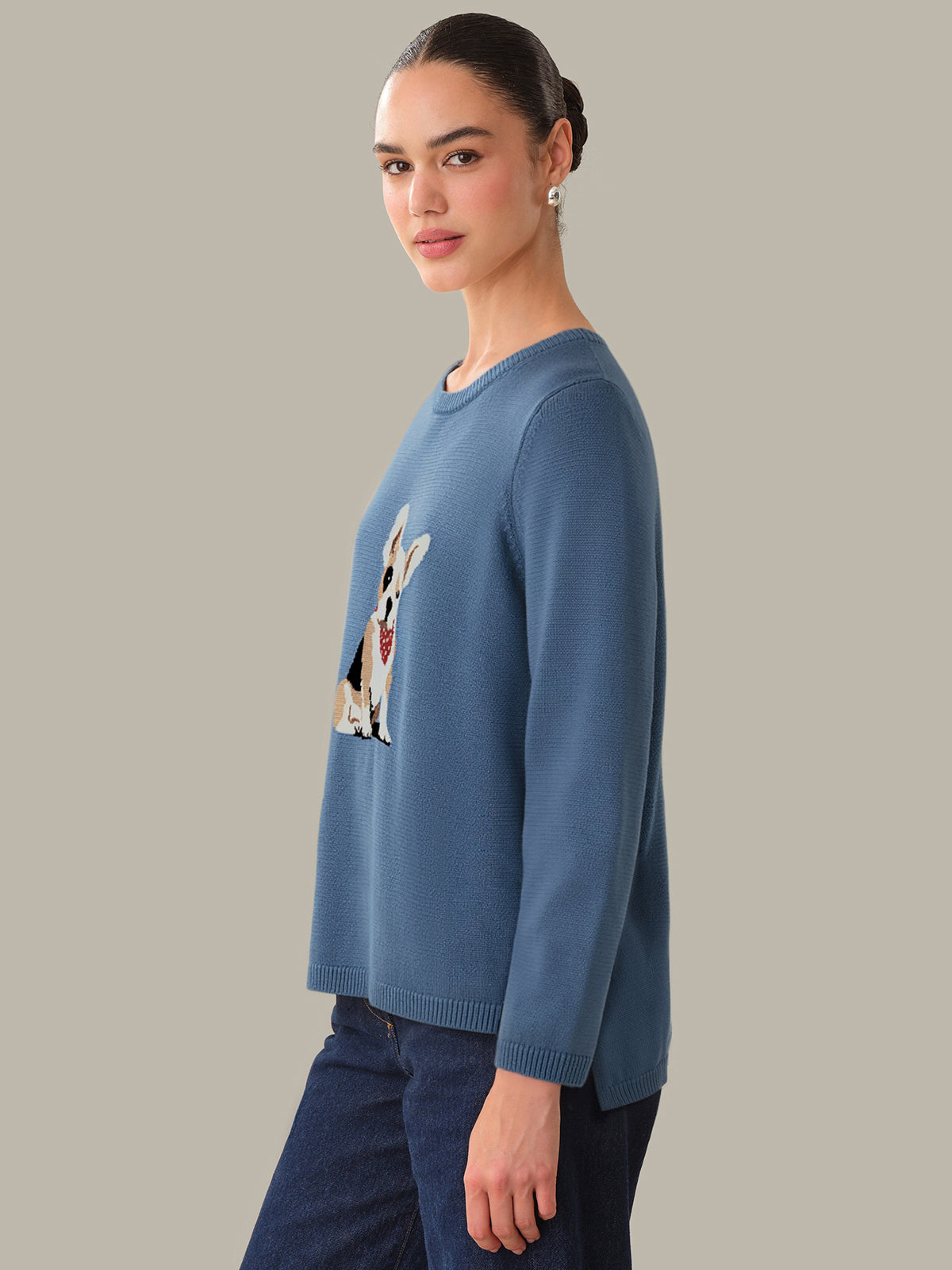 Woman wearing a blue sweater with a dog design on a plain background