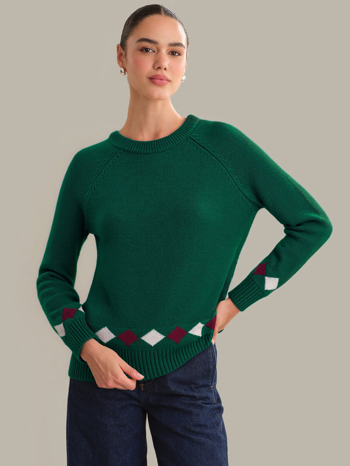 Woman wearing a green sweater with diamond pattern on a plain background