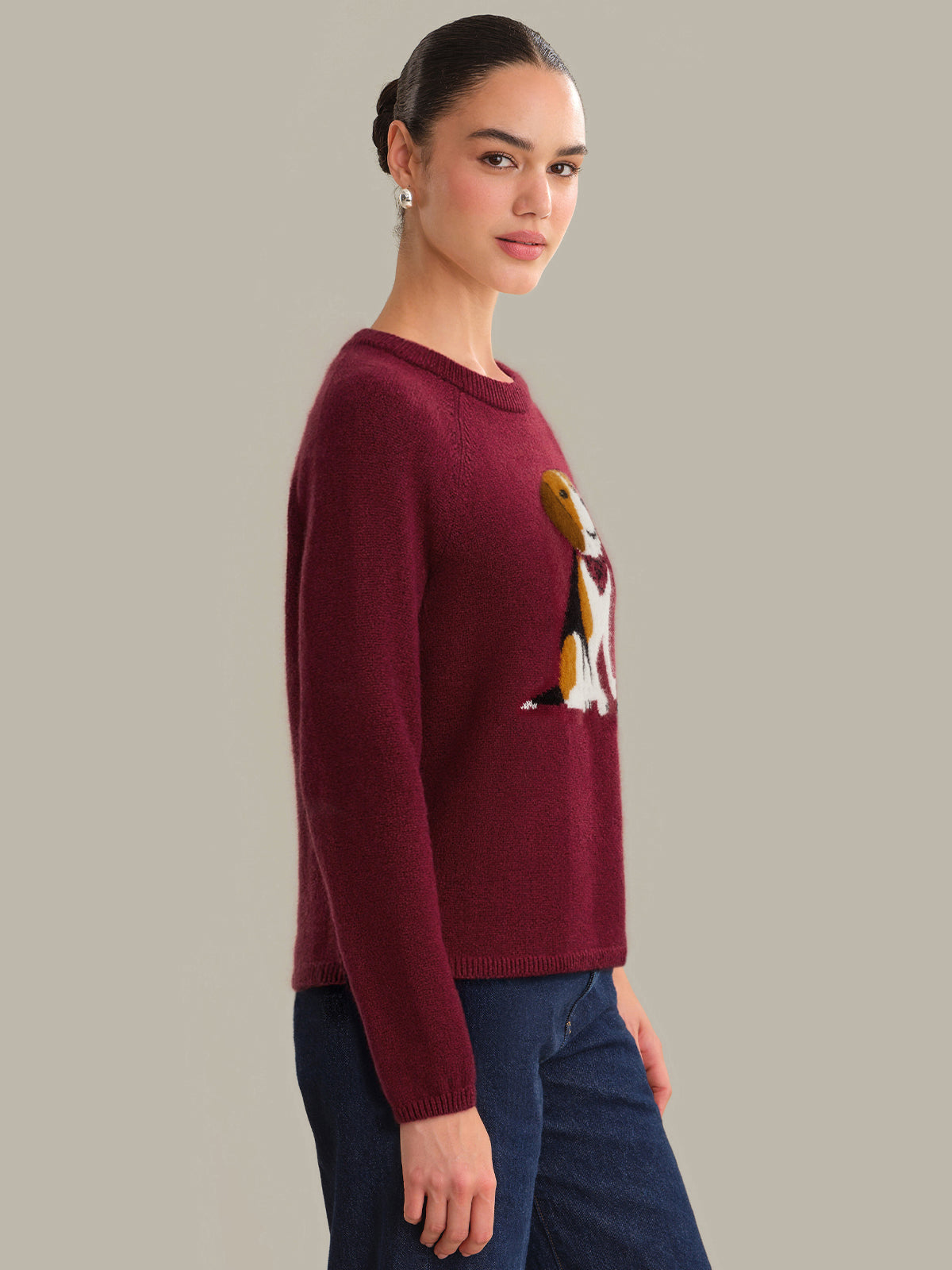 Woman wearing a burgundy sweater with a graphic design on a plain background