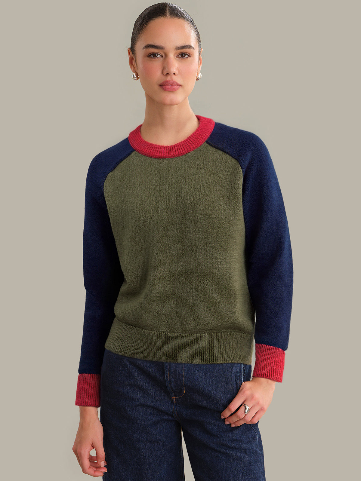 Person wearing a green and navy sweater with red accents on a beige background