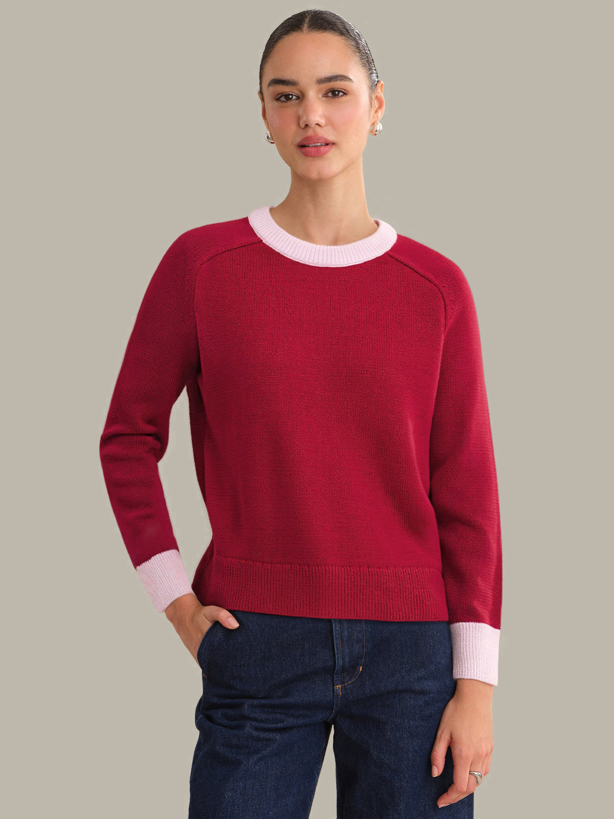 Woman wearing a red sweater with white trim on a plain background