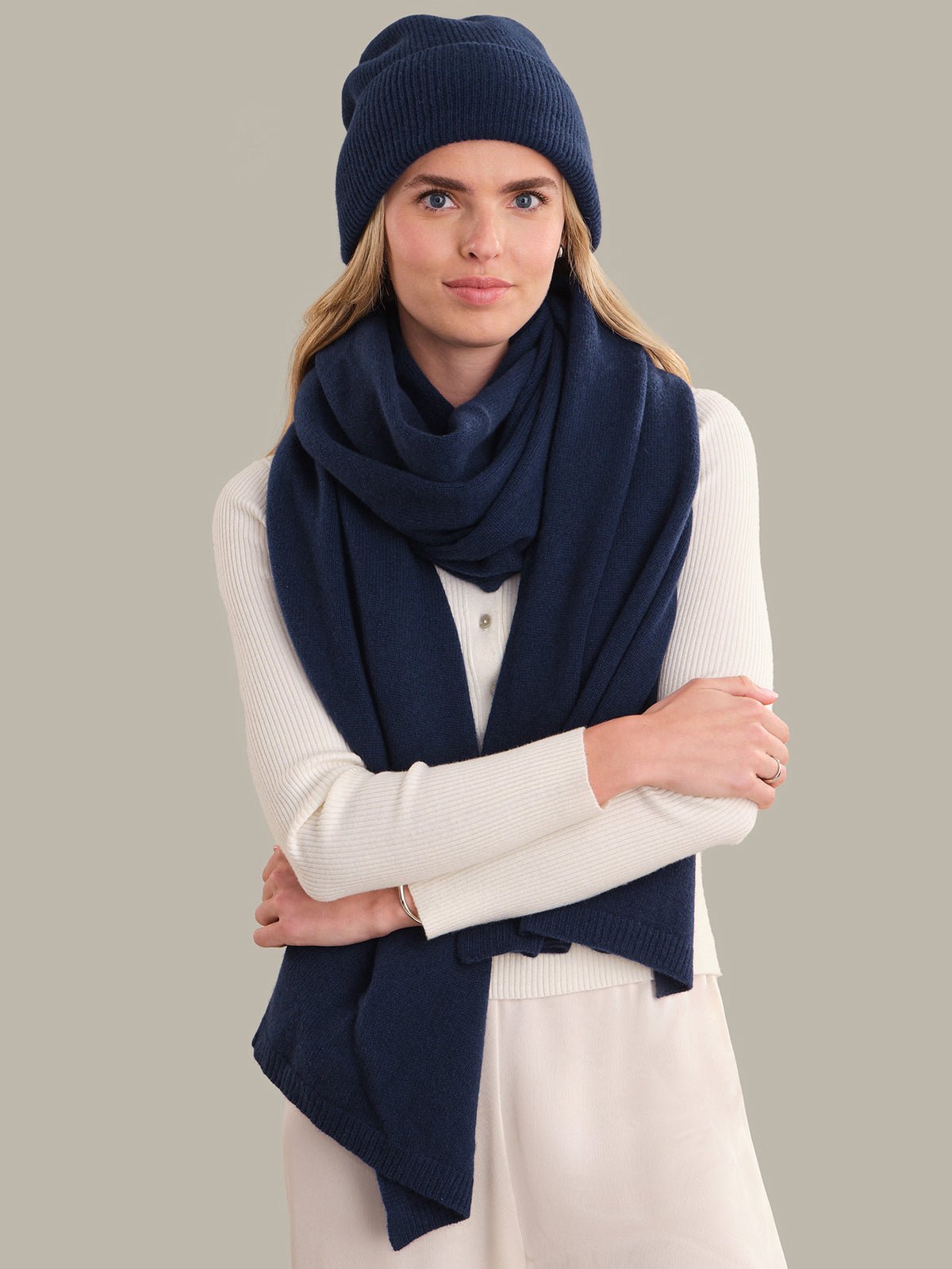 Woman wearing a navy blue scarf and beanie on a gray background