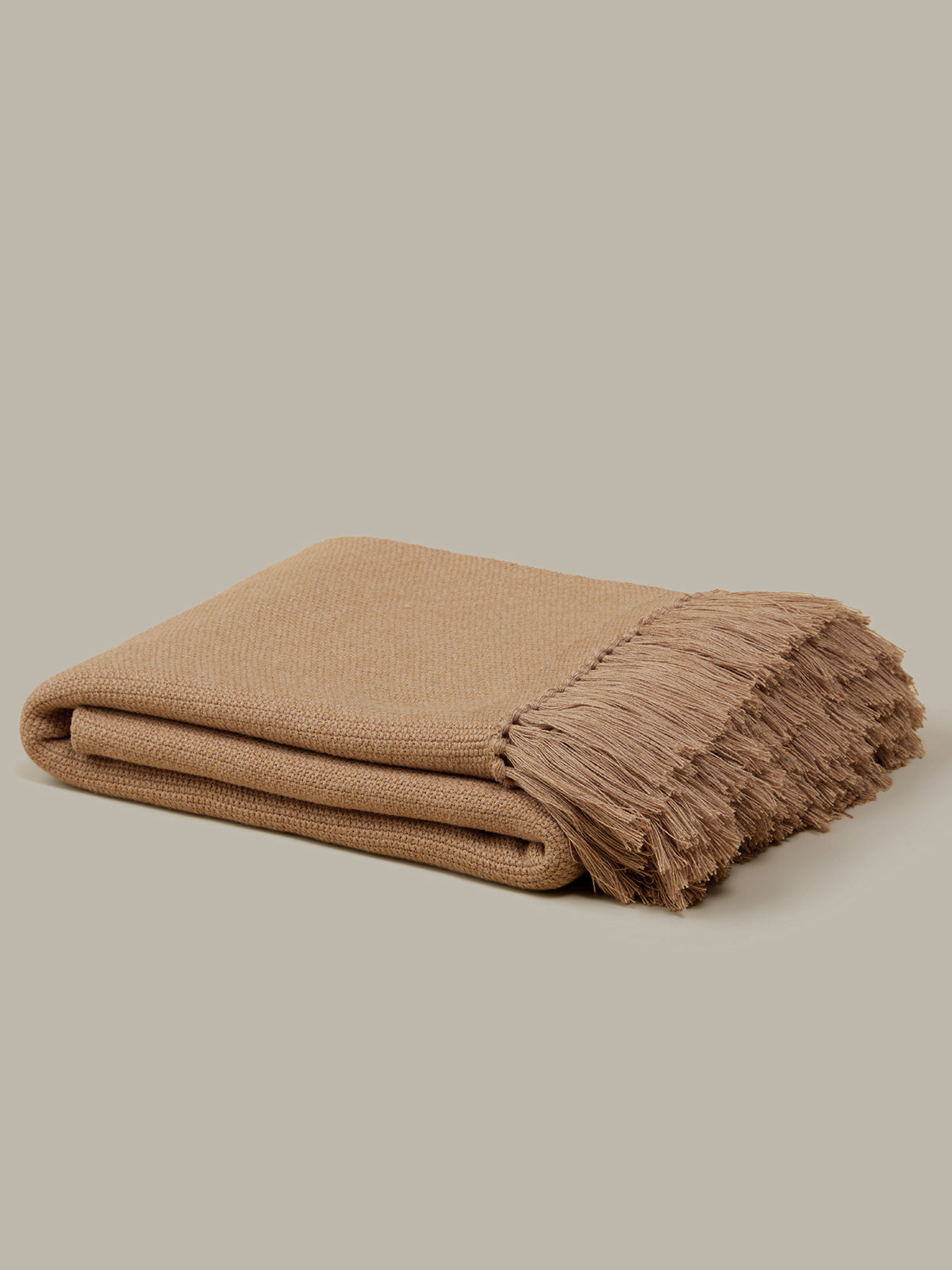 Beige blanket with frayed edge on a beige background