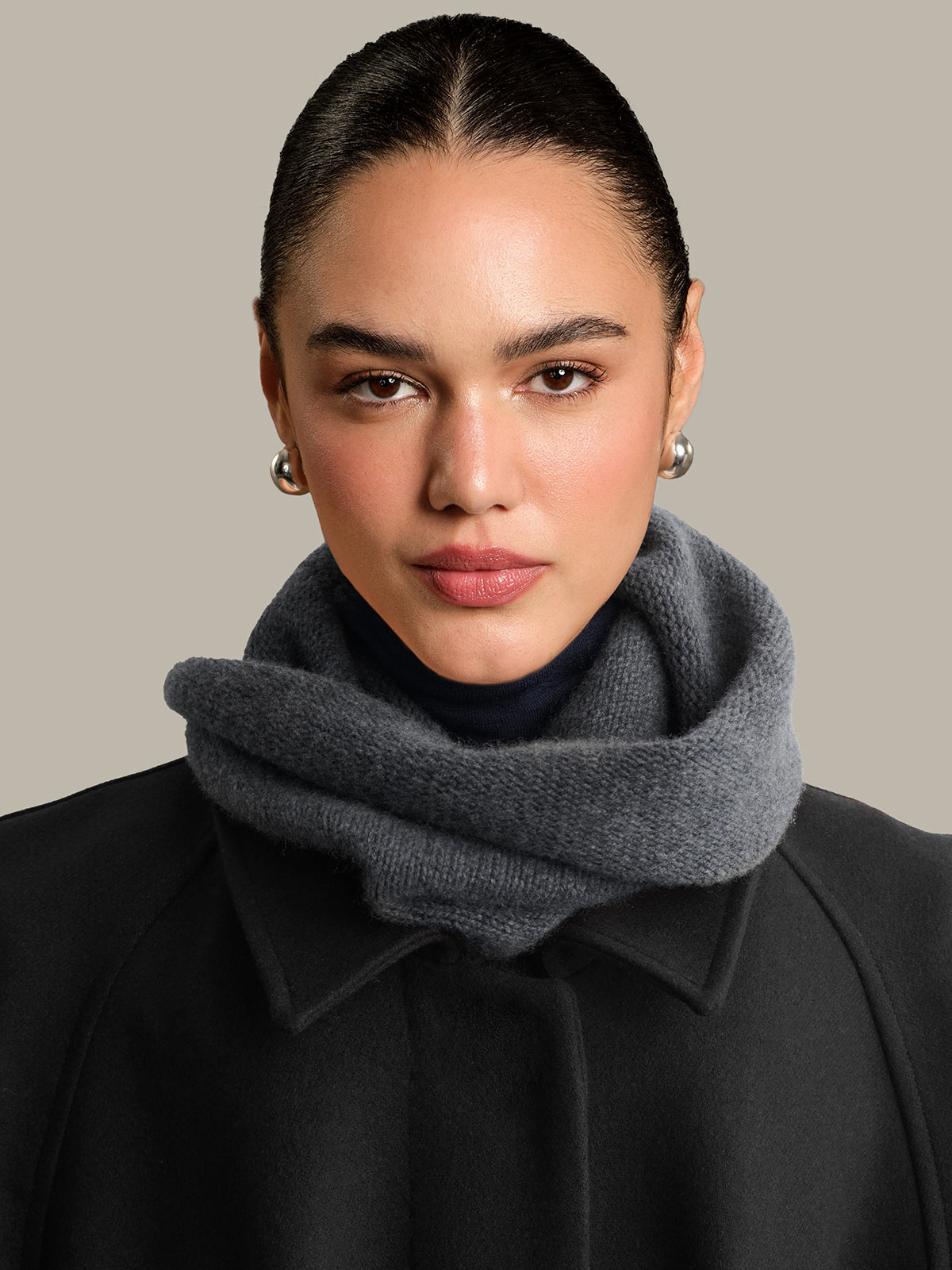 Woman wearing a gray scarf with a plain background