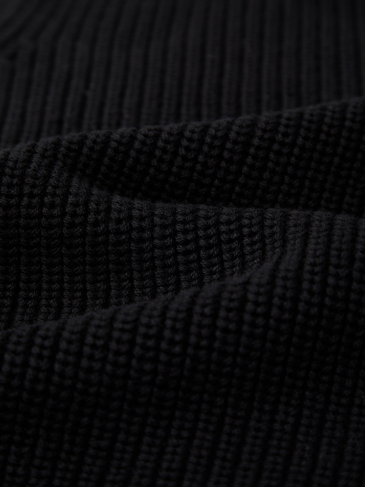 Close-up of black ribbed knit fabric by 525 America, highlighting its textured pattern and horizontal ridges—perfect for layering or creating a classic 100% cotton crew neck piece.