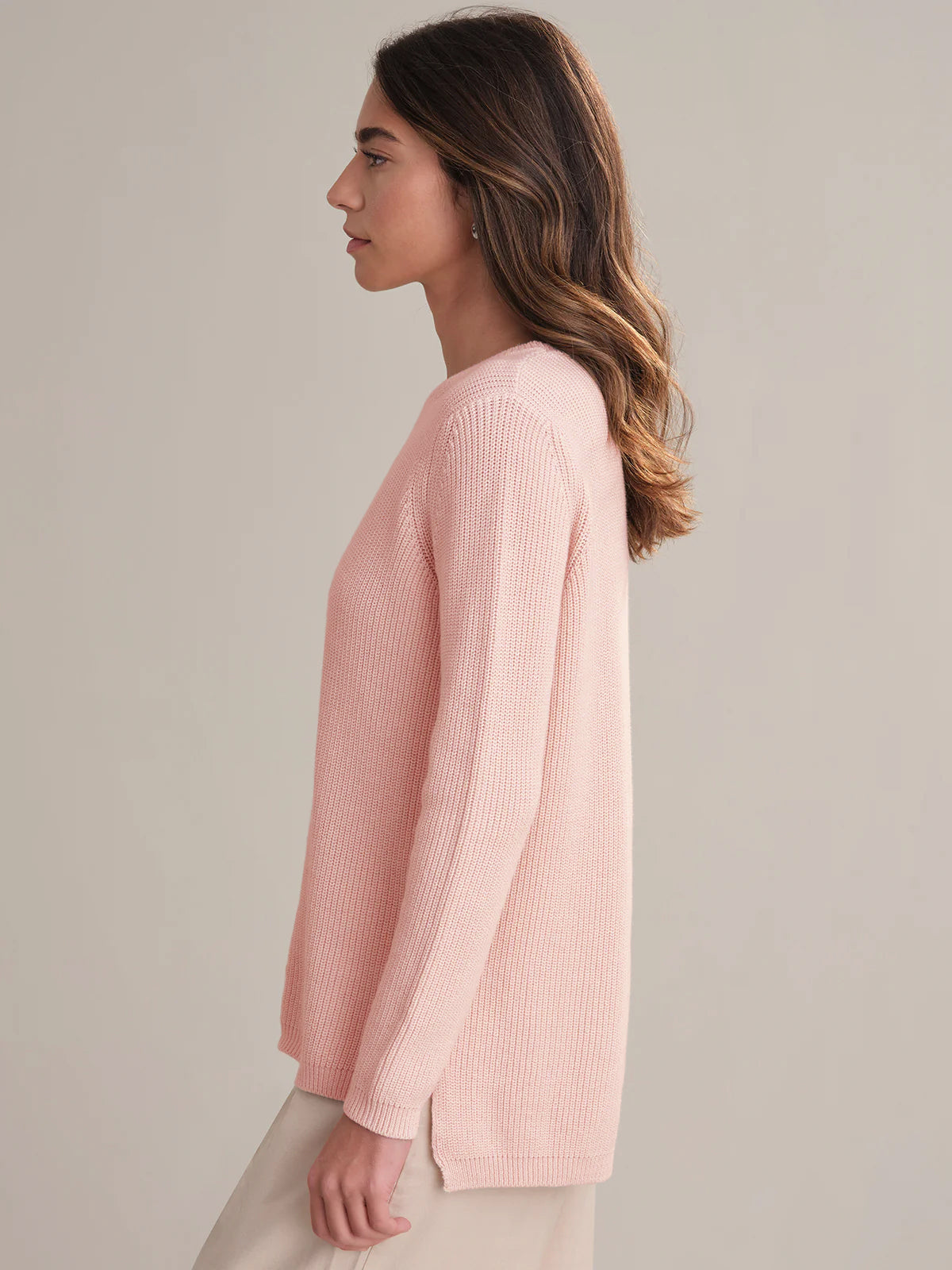 Woman wearing a light pink sweater against a neutral background