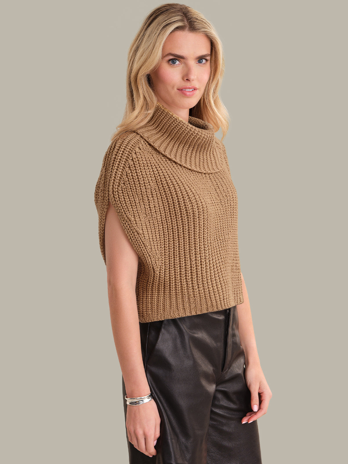 Woman wearing a brown knitted sleeveless sweater against a neutral background