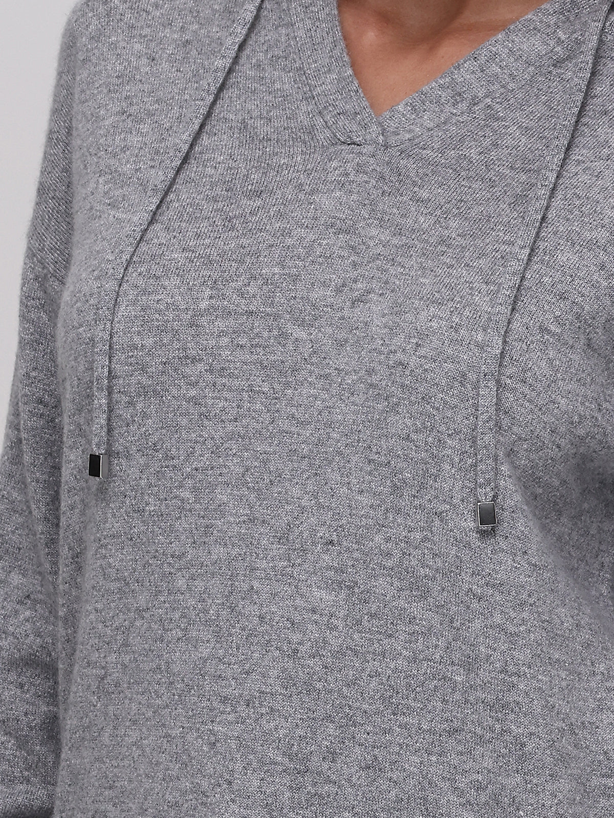 A close-up of a person wearing a 525 America cashmere knit V-neck sweater with two drawstrings finished with small metal tips. The persons face is not shown, highlighting this versatile piece perfect for any occasion.