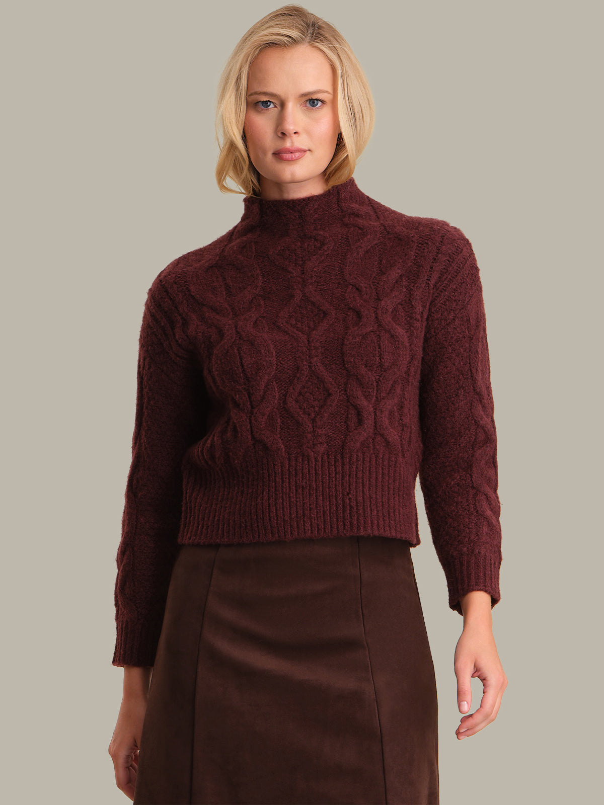 Woman wearing a maroon cable knit sweater against a neutral background