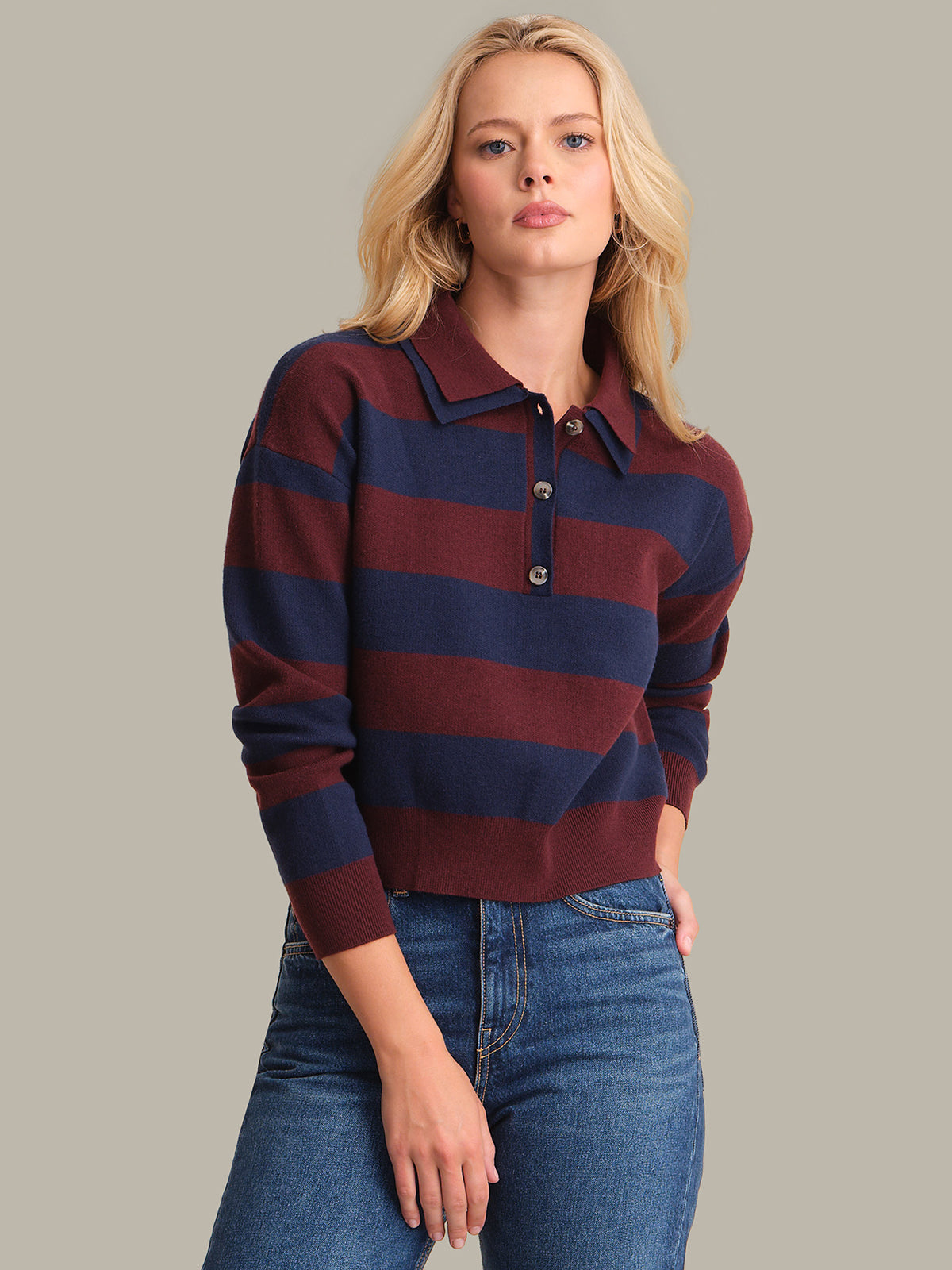 Woman wearing a striped sweater and jeans against a neutral background