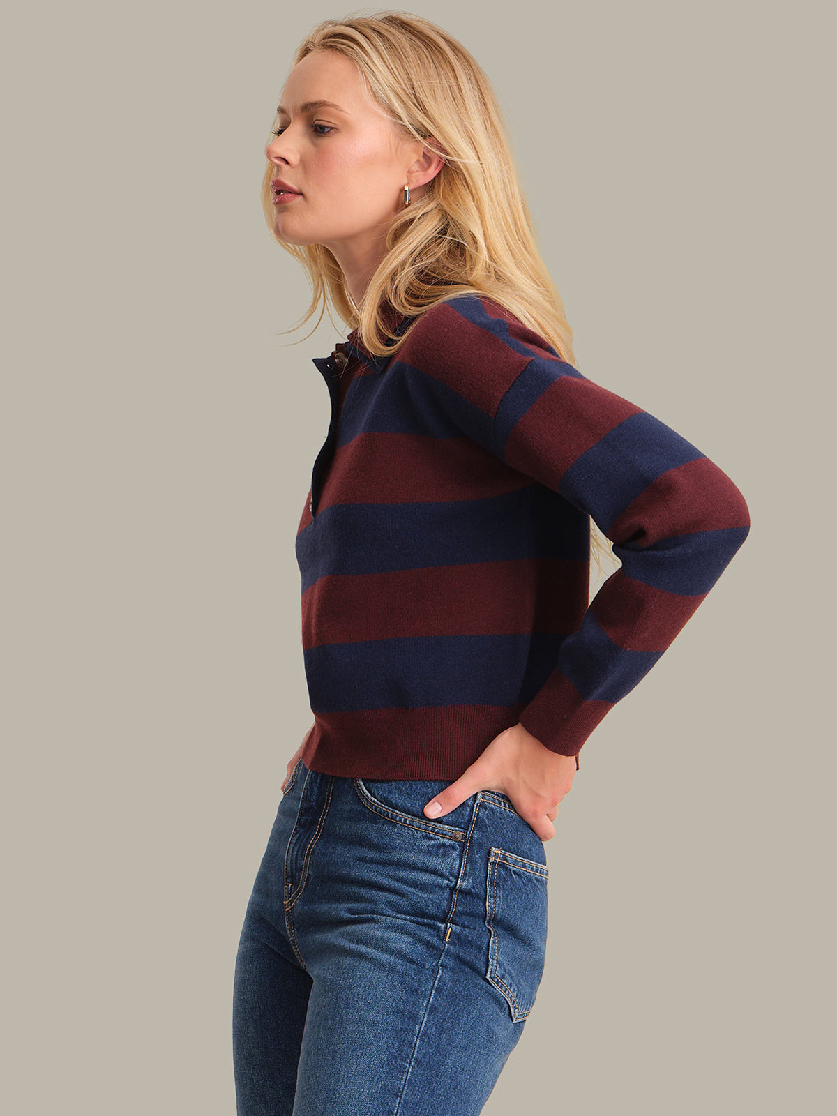 Woman wearing a striped sweater and jeans on a plain background